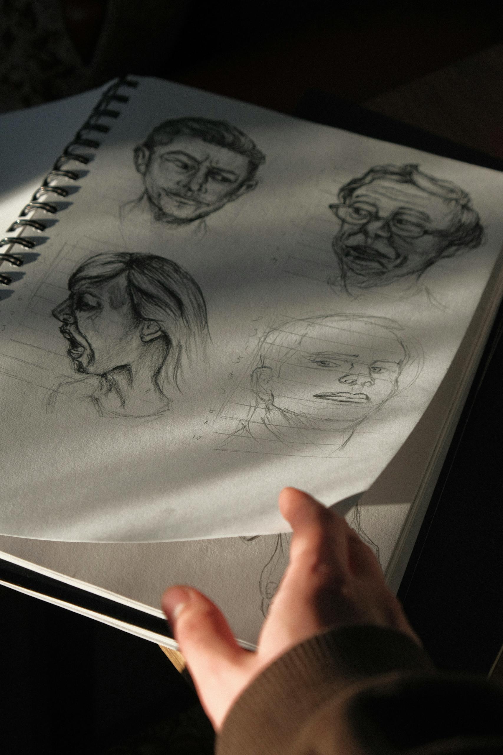 A notebook page with artistic pencil sketches captured in dramatic shadow and light.