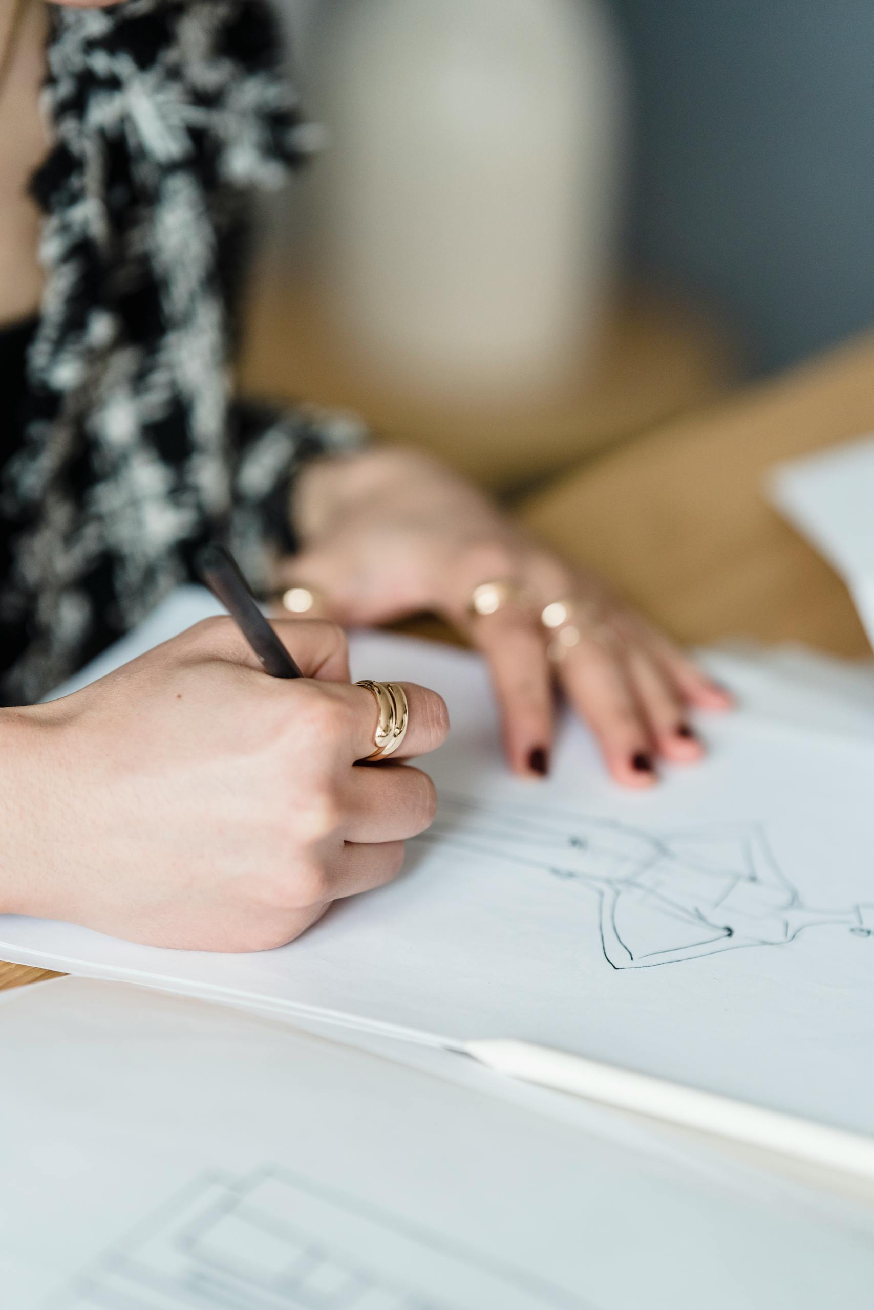 High angle of anonymous crop woman drawing sketch of female on paper against blurred background